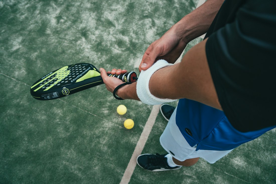 Joueur de padel avec sa raquette et ses balles sur le court